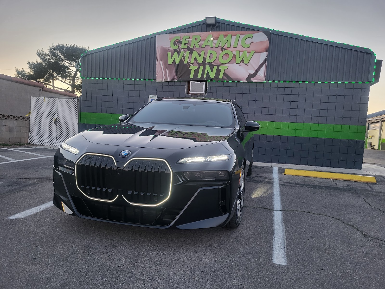 Black BMW 7 Series in front of a Ceramic Window Tint banner at the shop