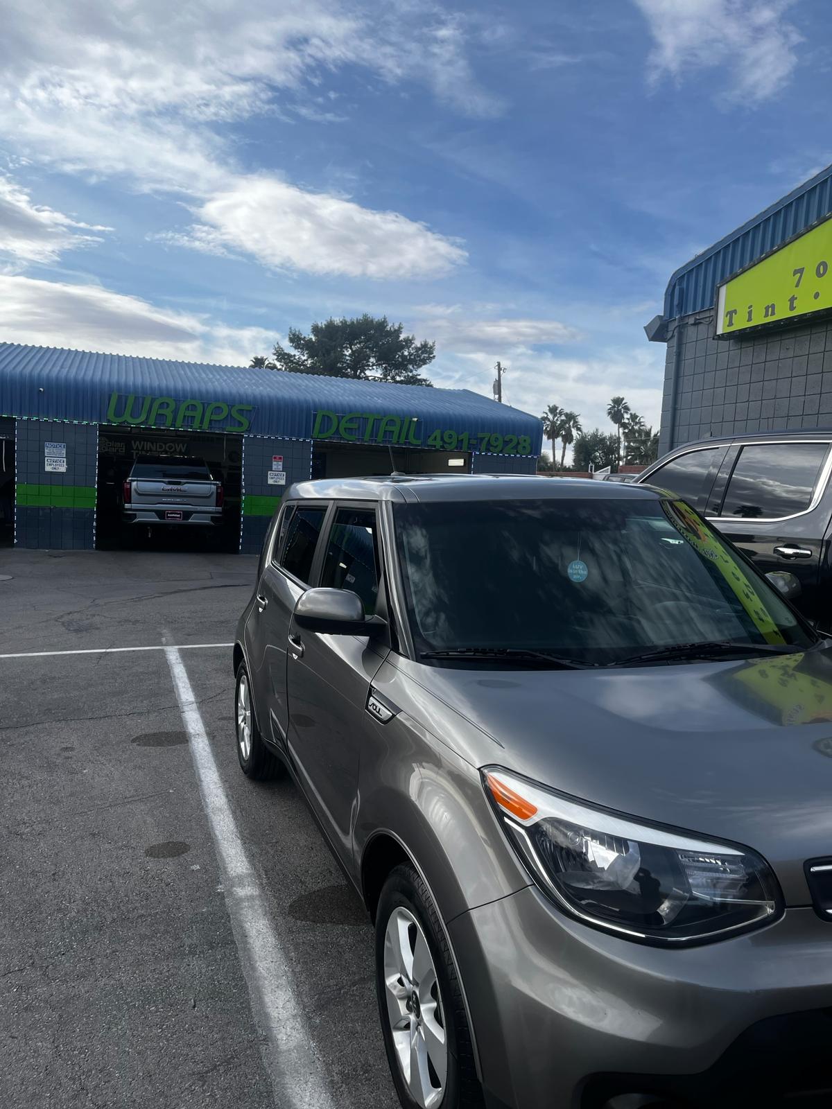Gray Kia Soul parked outside the shop with Wraps and Detail signage